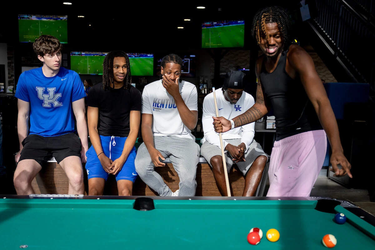 Kentucky basketball player Kam Williams shoots pool as teammates, from left, Reece Potter, Alex Wilkins, Justin McBride and Zoom Diallo watch during a team outing in Lexington.
