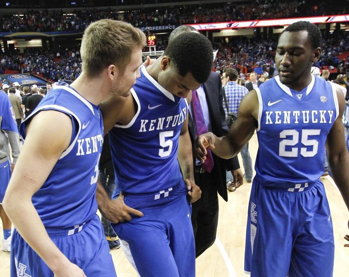Kentucky guard Andrew Harrison (5) was consoled by Jarrod Polson (3) and Dominique Hawkins after Florida beat Kentucky 61-60 in the SEC championship game in Atlanta in 2014.