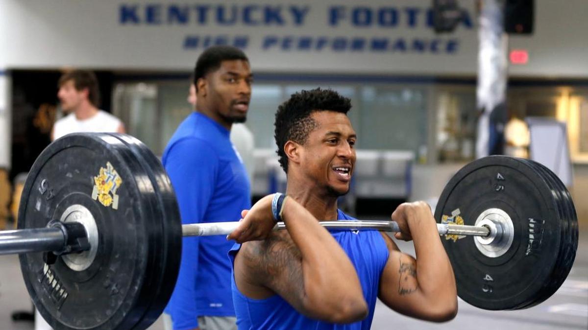 Redshirt freshman wide receiver Tavin Richardson lifted under the instruction of new UK strength and conditioning coach Mark Hill, background, as part of the University of Kentucky football team took part in a weightlifting session in the E. J. Nutter Training Facility on campus in Lexington, Ky., Friday, February 26 2016. UK strength and conditioning coach Corey Edmond and new assistant strength and conditioning coach Mark Hill worked with the players.