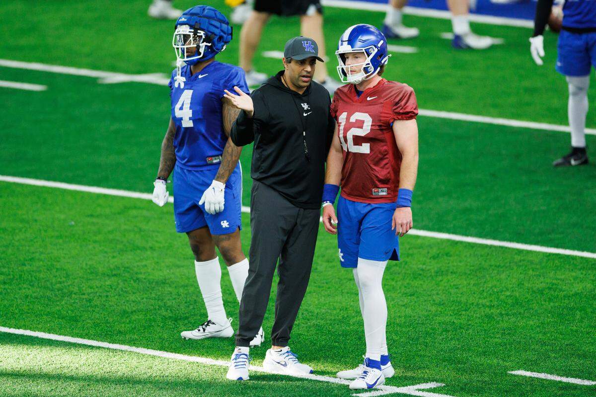 Quarterback Brock Vandagriff and offensive coordinator Bush Hamdan chat between plays during Kentucky football’s first spring practice.