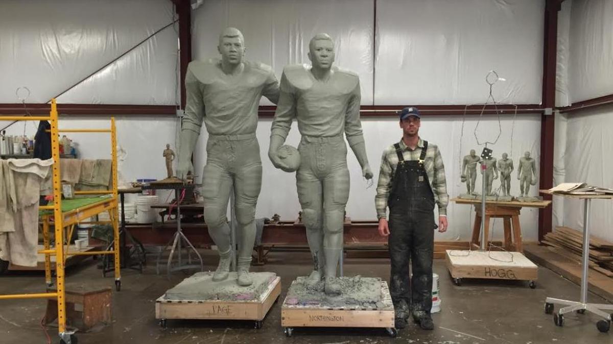 Sculptor J Brett Grill with the statues he created of former Kentucky Wildcats Greg Page, left, and Nate Northington, the first two black football players to sign with a Southeastern Conference school.