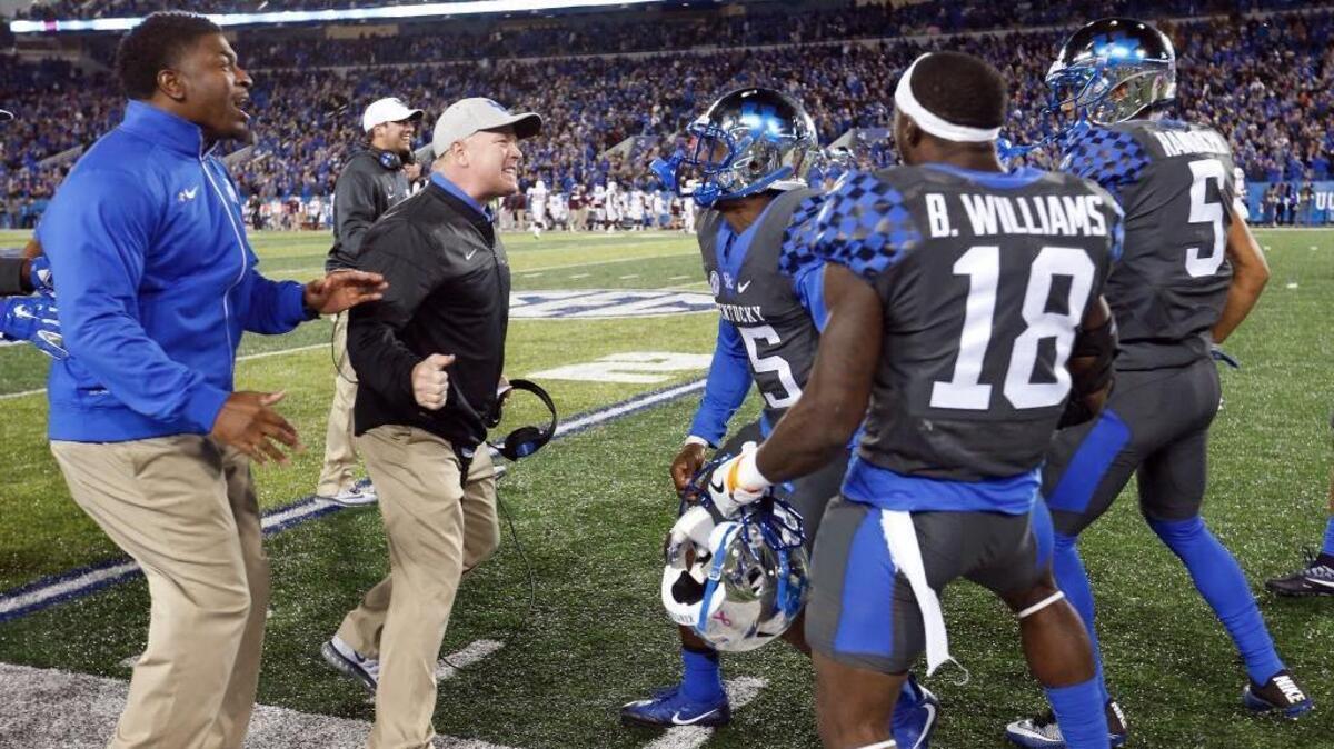 Kentucky head coach Mark Stoops congratulated safety Marcus McWilson (15) after he scored on an interception Saturday.