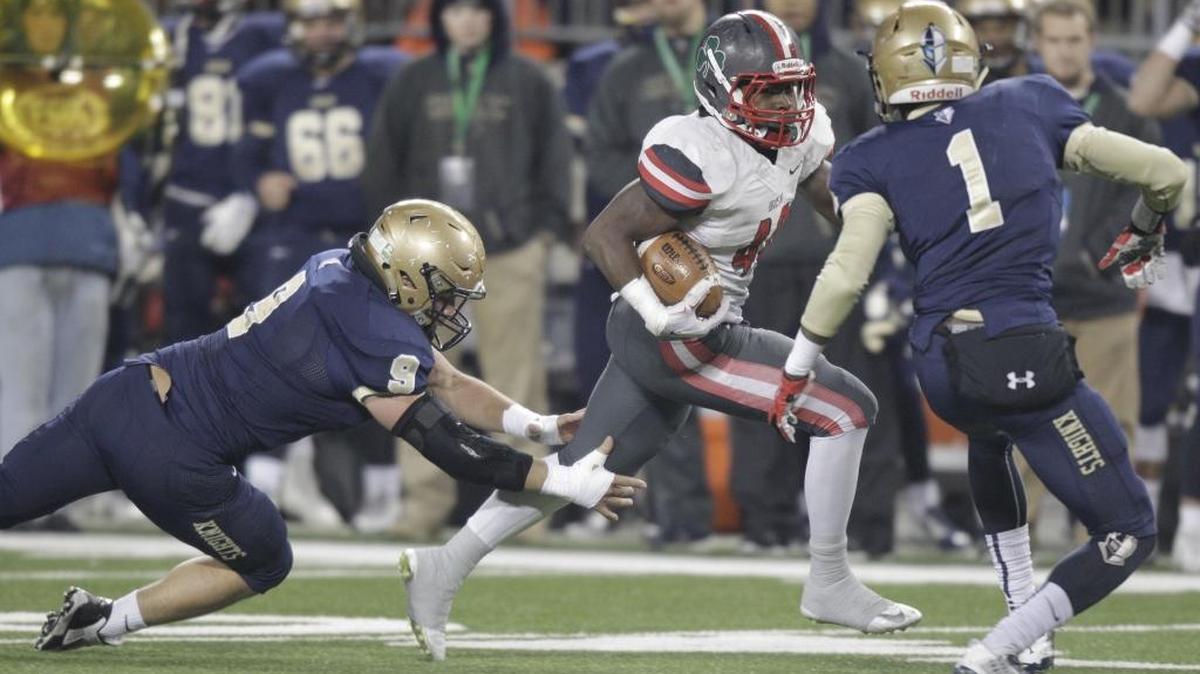 Toledo Central Catholic’s Michael Warren, center, tried to run past Akron Archbishop Hoban’s Marc Westover, left, and Jonah Morris during the first half of the OHSAA Div. II championship high school football game Thursday, Dec. 3, 2015, in Columbus, Ohio.