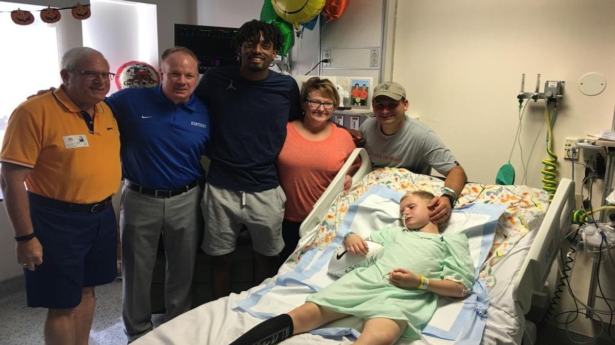 From left, grandfather Al Green, Kentucky Coach Mark Stoops, quarterback Stephen Johnson, Julie Burgett and dad Doug Green, posed for a picture next to the bed of Dalton Green, who is recovering from a serious infection.