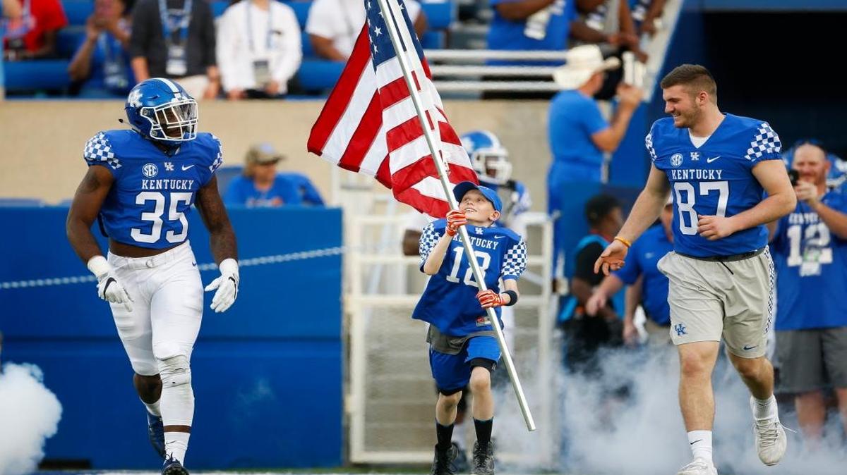 Ryan Cremeen, 9, of Richmond, Ky., carries the American flag onto the field with Kentucky defensive end Denzil Ware (35) and Kentucky tight end C.J. Conrad (87) during the 2017 UK Blue-White Spring Game on April 14, 2017. Both Ware and Conrad have been named to coaches’ preseason all-SEC teams.