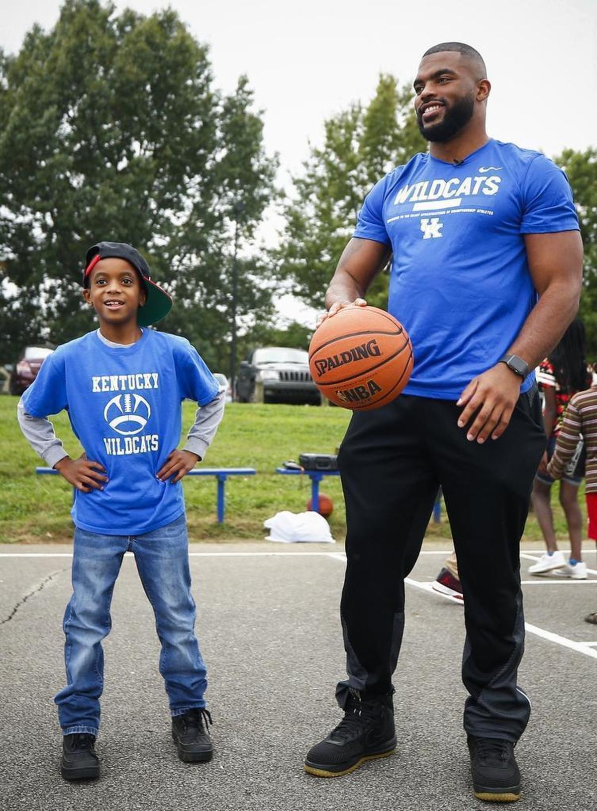 Antonio McKinney, 8, of Lexington, Ky., stands with University of Kentucky football player Courtney Love at Woodhill Park in Lexington, Ky., Thursday, Oct. 12, 2017. Love was recently named to the 2017 Allstate AFCA Good Works Team. He's one of 22 college football players across the country to receive this award specifically for his work with children whose parents are in prison.