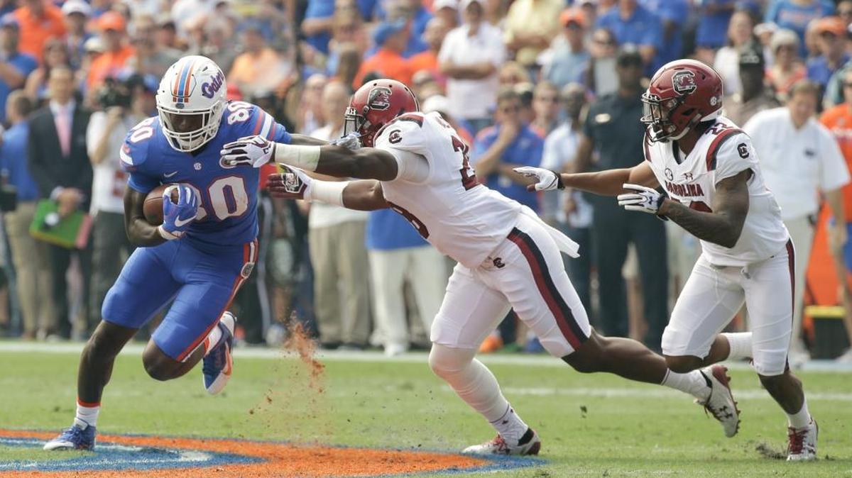 Florida tight end C'yontai Lewis (80) runs after a reception as he tries to get around South Carolina linebacker Jonathan Walton, center, and defensive back Steven Montac, right, during the first half of an NCAA college football game, Saturday, Nov. 12, 2016, in Gainesville, Fla.