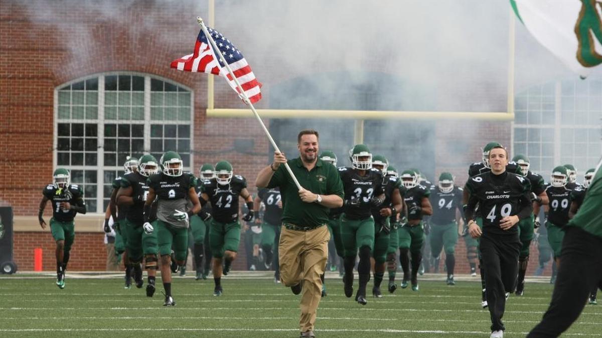 Dylan Ratliff, right, son of late Charlotte offensive line coach Phillip Ratliff, helps U.S. Rep. Richard Hudson, R-NC, lead the 49ers on the field before they played Marshall.