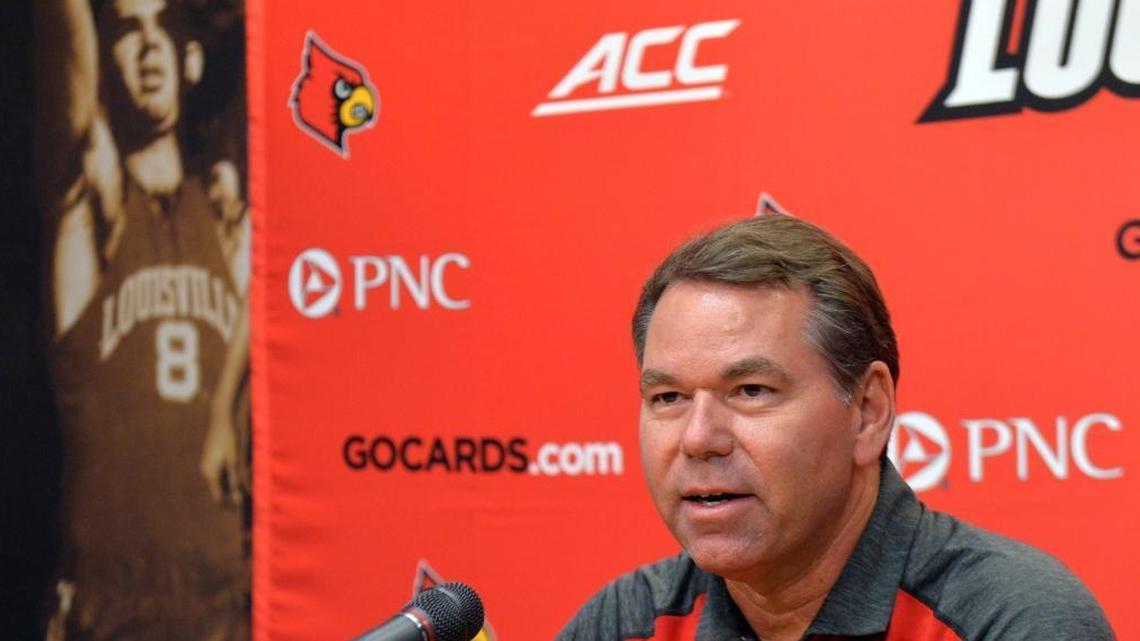 Louisville interim athletic director Vince Tyra answered questions during a news conference, last October in Louisville. Behind Tyra is a photograph of Tyra’s father, Charlie Tyra, who played for Louisville from 1954-57.