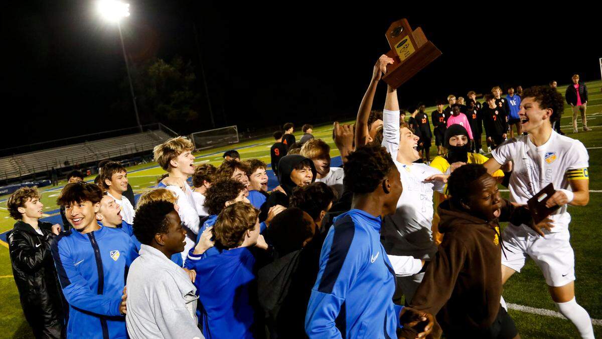 Henry Clay’s Marco Messerli holds the boys 11th Region soccer championship trophy aloft as he and his teammates celebrate their 2-0 win over Frederick Douglass in the finals at Henry Clay High School on Friday.