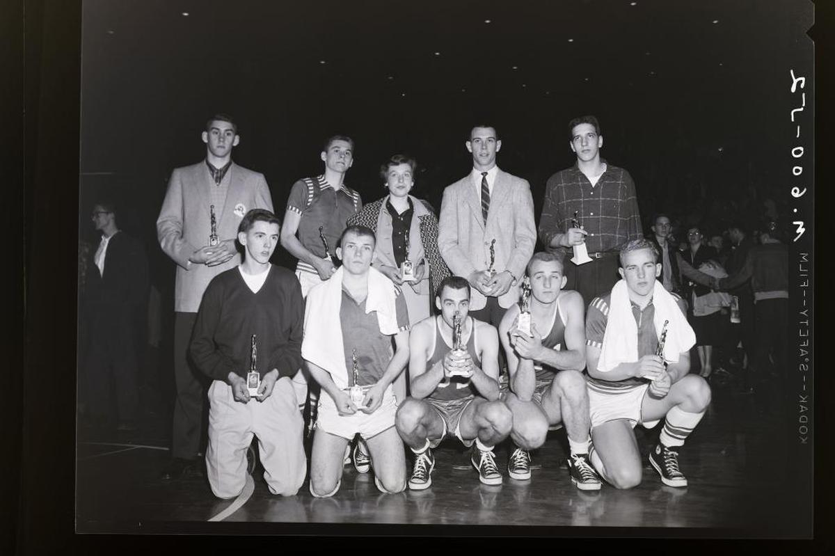 The 1956 All-State High School Basketball Tournament team, plus the sister of Kelly Coleman, who accepted the gift in King Kelly’s absence. Front row, left to right, Rex Story, Mayfield; Dave Eakins, Henderson; E.A. Couch, Carr Creek; Bobby Shepherd, Carr Creek; Pascal Benson, Henderson; back row, Harry Todd, Earlington; Byron Pinson, Henderson; Linda Coleman, Wayland; Corky Withrow, Central City, and Billy Ray Lickert, Lafayette. Photo was taken after Carr Creek defeated Henderson 72-68 for the state title on March 17, 1956 in Memorial Coliseum.