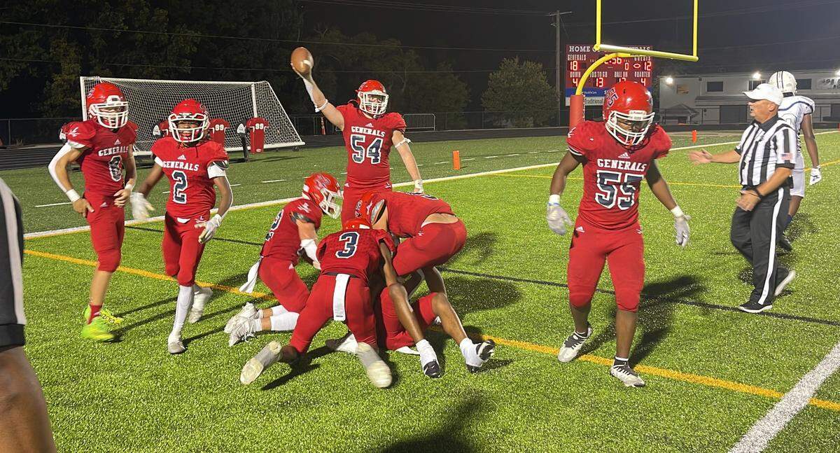 Lafayette’s Cael Green holds up the football in celebration of teammate Nasir Andrews’ 25-yard interception return for a touchdown as his fellow teammates swarmed Andrews on the ground at Ishmael Stadium on Friday.