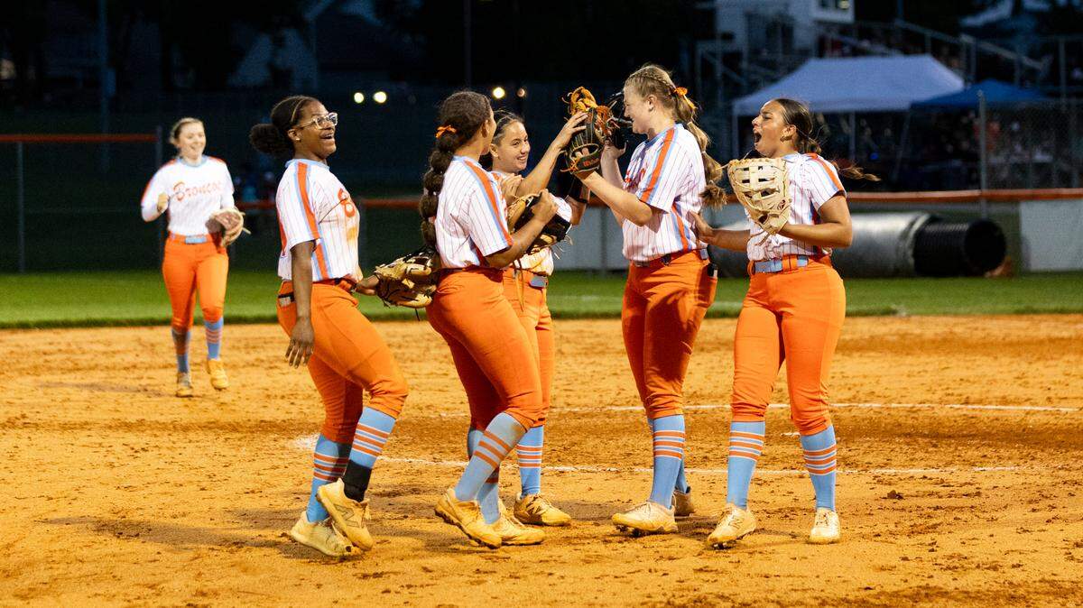Frederick Douglass’ Emma Dunn and Haley McGuire, center left and right, touch gloves as their teammates gather to celebrate the Broncos’ 8-2 win against Scott County in the 42nd District Tournament championship game at Frederick Douglass on Wednesday.