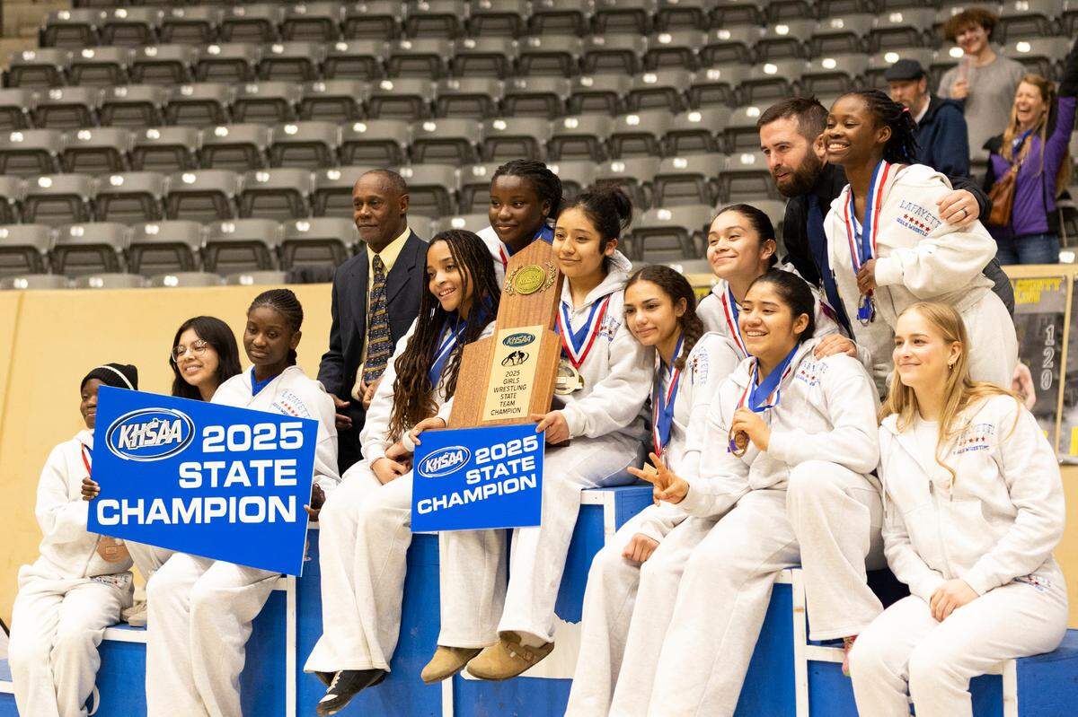 Lafayette’s Amy Velasco, center, held the 2025 KHSAA Girls Wrestling State Championships team trophy as she and her teammates and coaches William Green, at left, and Luke Rearic posed for photographers at Alltech Arena on Thursday.