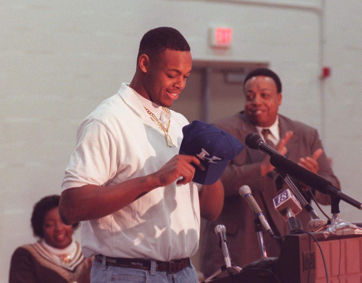 Dennis Johnson, flanked by his parents, prepared to put on a University of Kentucky hat after he announced his commitment during a press conference at Harrodsburg High School in 1998.