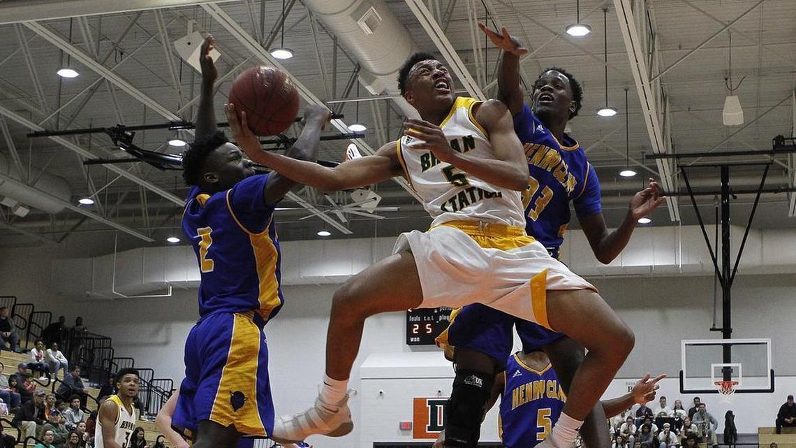 Bryan Station’s Eric Boone put up a shot Wednesday against Henry Clay’s Terron Hughes, left, and Andreus Green during the boys’ 42nd district tournament at Frederick Douglass.