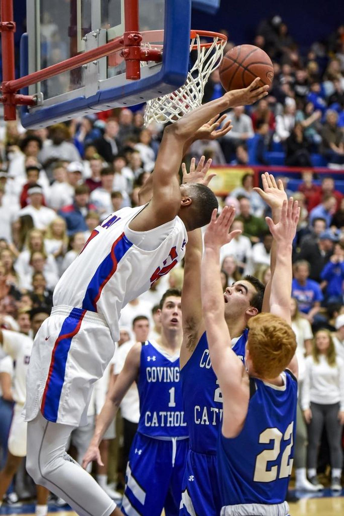 Madison Central's Isaiah Cozart (50) shoots around Covington Catholic's AJ Mayer (21), center, and Aiden Ruthsaltz (22), right, February 16, 2018, at Madison Central High School in Richmond.