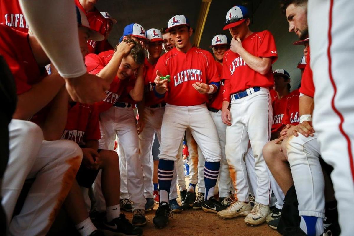 Members of the Lafayette baseball team entertain themselves in the dugout with rocks and a fidget spinner during a rain delay in the 2017 43rd District baseball tournament.