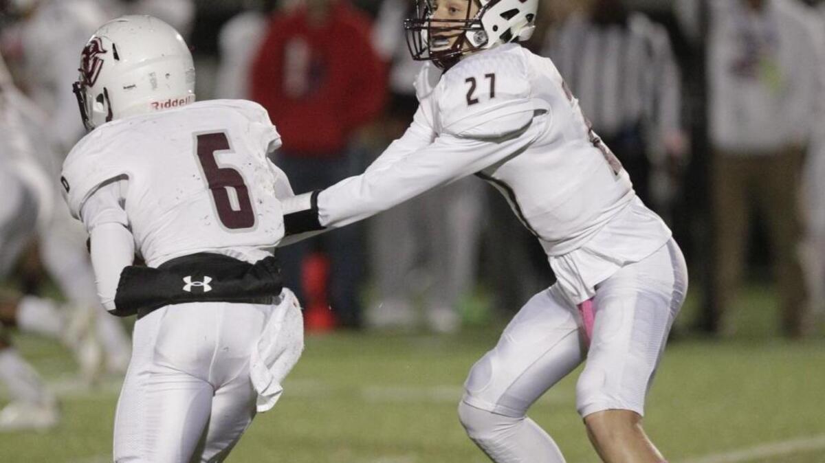 Tates Creek freshman quarterback Luke Duby (27) handed the ball off to junior Laron Warner during the Commodores’ game at Lafayette on Friday, Oct. 21, 2016.