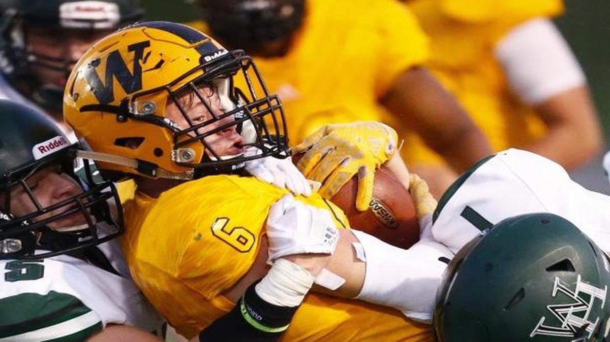 Western Hills' Chandler Johnson (5) and Wandale Robinson (1) brought down Woodford County's Benjamin Nash (6) on Friday. Western Hills topped the Yellowjackets 47-24.