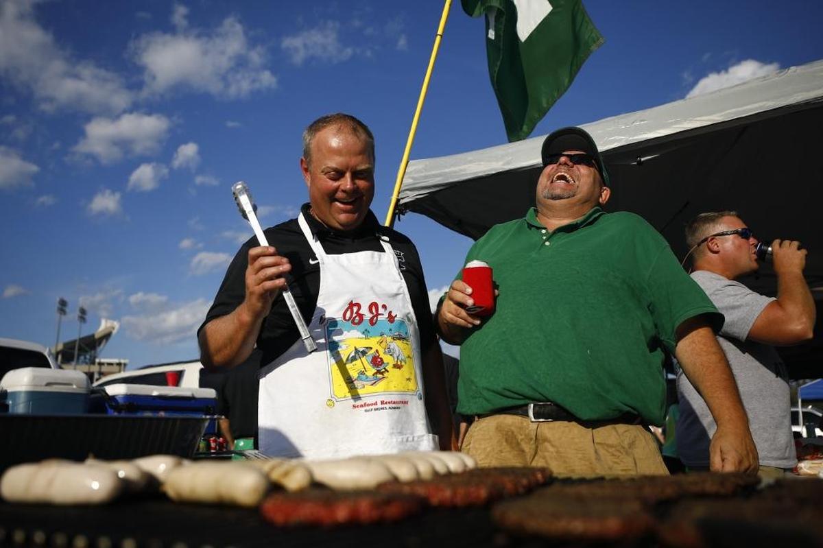 B.J. Ruckriegel, left, and Tom Smith, both of Louisville, Ky., laugh at Ruckriegel's tailgating site before a game between Trinity and St. Xavier at Papa John's Cardinal Stadium in Louisville, Ky., Friday, Sept. 29, 2017. Ruckriegel graduated from Trinity in 1995 and usually draws a crowd of about 400 people to his tailgating site.