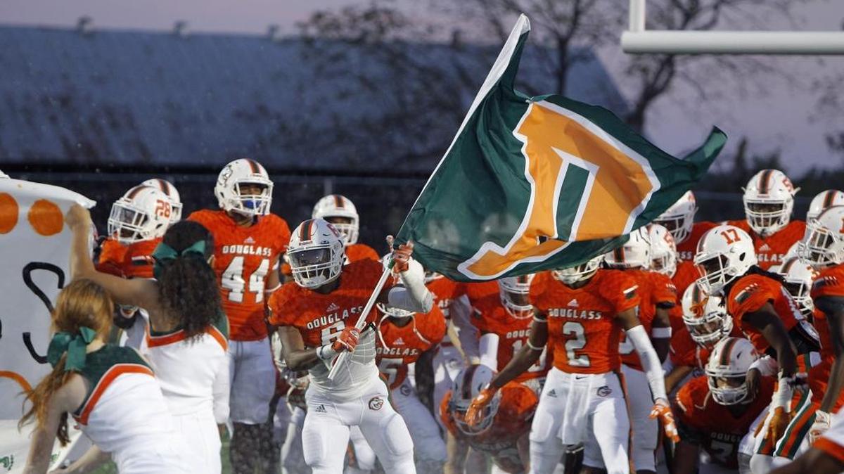 Frederick Douglass’ Maliq Trigg waved the school flag before taking the field against Bryan Station at Frederick Douglass High School last September. The Broncos went 7-0 against Fayette County competition in their inaugural season last year.