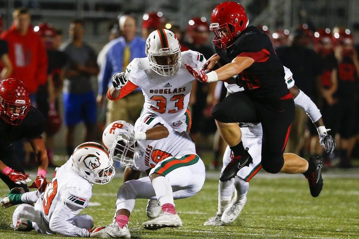 Scott County's Austin Barnett (20) leaps past Frederick Douglass' Jaylin Bybee (28) Frederick Douglass' Devin Neal (33) Frederick Douglass' Daiyaan Perkins (19) and Frederick Douglass' Shamarr Taylor (9) during their game at Toyota Stadium in Georgetown, Ky., Friday, Oct. 6, 2017. Scott County beat Frederick Douglass 55-21.