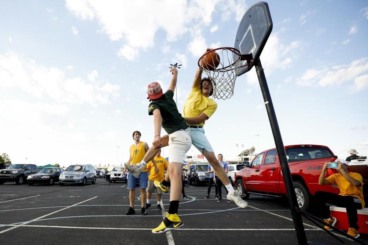 St Xavier students Ethan Hans, 17, right, dunks a basketabll over his brother Logan Hans, 15, both of Louisville, Ky., while tailgating before a game between Trinity and St. Xavier at Papa John's Cardinal Stadium in Louisville, Ky., Friday, Sept. 29, 2017. Trinity beat St. Xavier 28-0.
