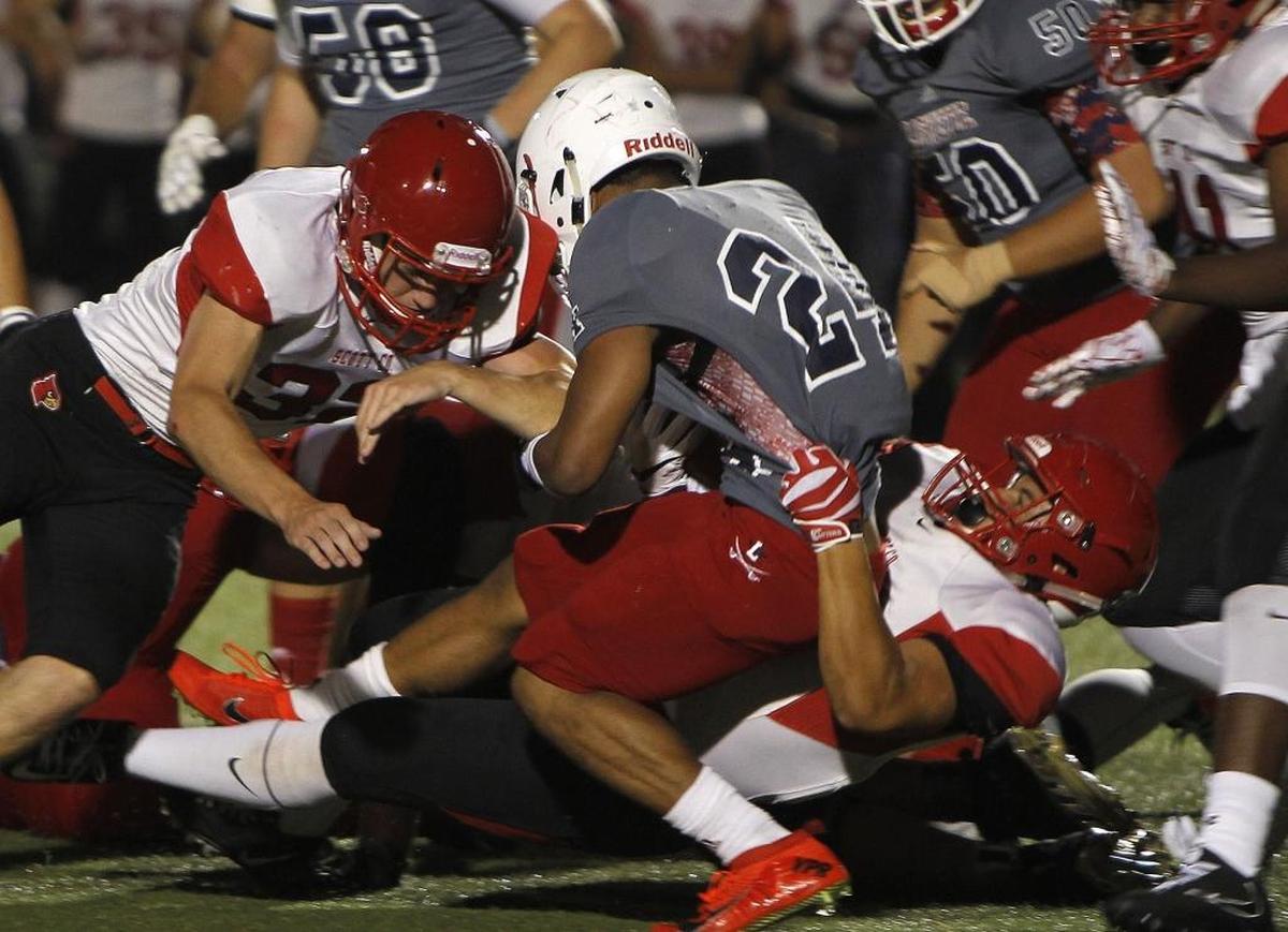 Lafayette's Cameron Morgan is pulled down by Scott Co. defenders in the Blanton Collier Kickoff Classic at Ishmael Stadium in Lexington, Ky., Friday, August 25, 2017.