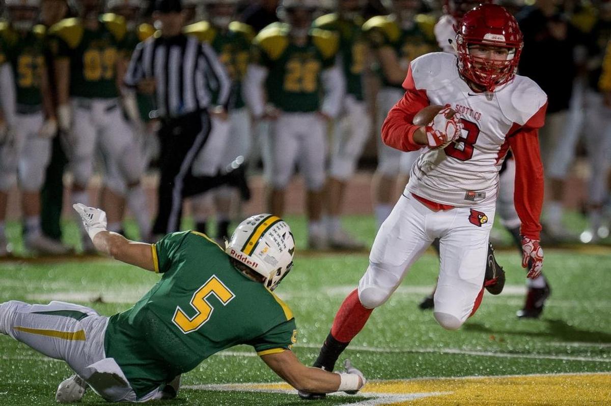 Scott County Cardinal's Brice Fryman (3) is tripped up by Saint Xavier TIger's Jake Netherton (5)during the Kentucky State 6A semifinal football game in Louisville, Kentucky, November 24, 2017.