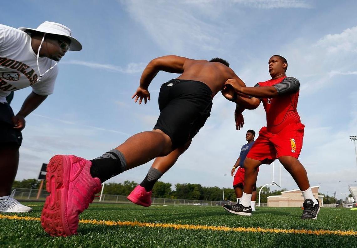 Defensive line coach Derrick Thomas, left, looked on as defensive lineman Dayton LeBlanc, right, worked against Cameron Kennedy, middle, in a drill during Frederick Douglass High School’s football practice at the new school, 2000 Winchester Rd. in Lexington, Ky., Friday, July 14, 2017. The school will open this fall.