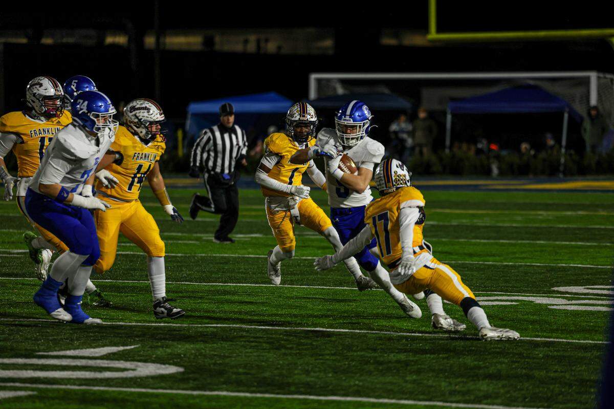 Franklin County’s defense, including Jeremy Walters (14), Elesius Robinson (1) and Hunter Gotshall (17), swarmed Covington Catholic’s Dylan Gaiser during the Flyers’ 14-10 win in the Class 4A state semifinals in Frankfort on Friday.