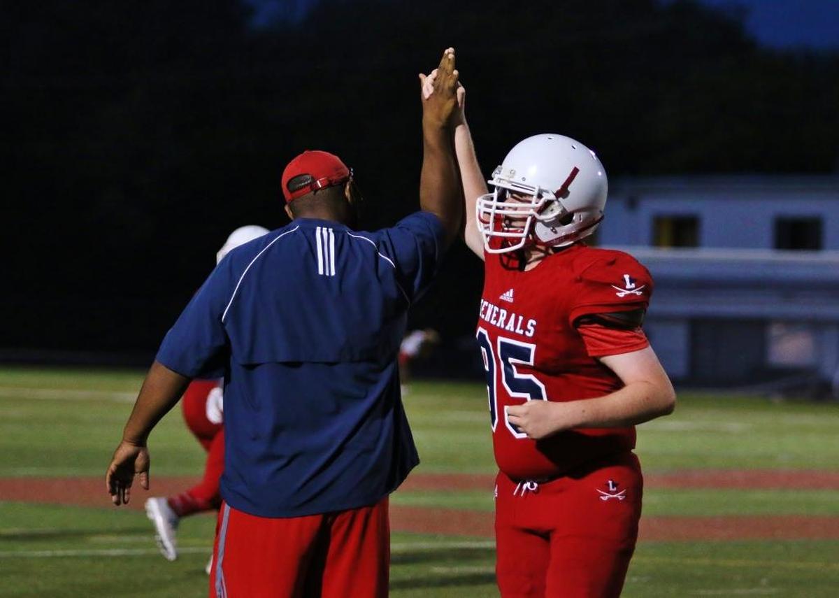 Lafayette High School defensive lineman Will Watkins, right, high-fived assistant coach Matt Brown after the Generals’ scrimmage versus Woodford County High School in August.