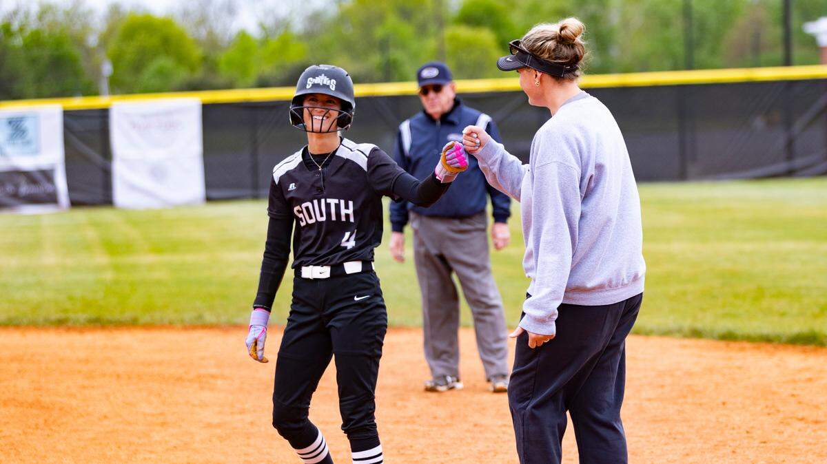 South Warren first base coach Julianne King, right, congratulates Hadley Borders (4) after her hit against the host Cardinals at Scott County on Saturday.