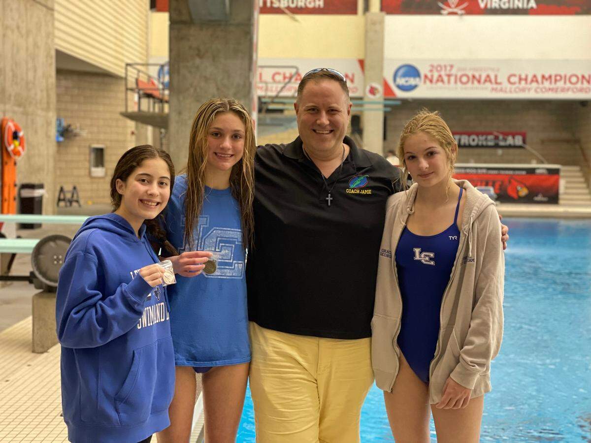 Lexington Catholic diving coach Jamie Palumbo poses with his girls team, from left, Yasemine Stephens, Sydney Leslie and Grace George after the Region 8 Diving Championships at the University of Louisville on Monday, Feb. 5, 2024.