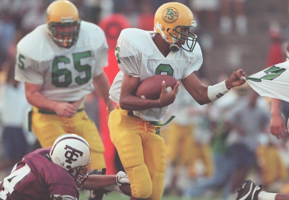 Bryan Station quarterback J.T. Haskins (3) grabs on to his teammate as Tates Creek’s Justin Seal (84) tries to tackle him during the first quarter at Tates Creek High School on Friday, Sept. 4, 1998.