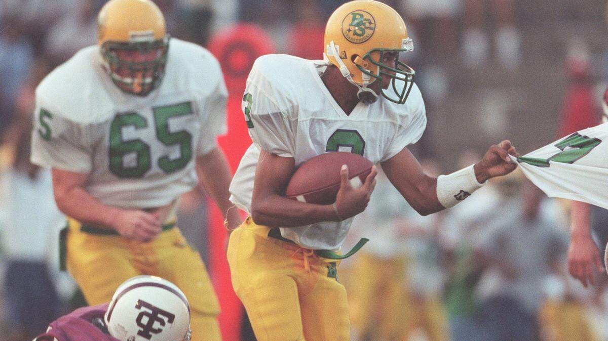 Bryan Station quarterback J.T. Haskins (3) grabs on to his teammate as Tates Creek’s Justin Seal (84) tries to tackle him during the first quarter at Tates Creek High School on Friday, Sept. 4, 1998.