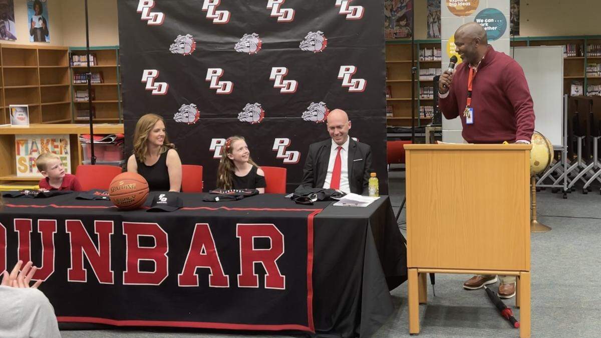Paul Laurence Dunbar High School Athletic Director Murray Garvin, right, introduced new Bulldogs head basketball coach John Morgerson in the school’s library on Thursday. Seated with Morgerson are his wife, Whitney, son, Eli, and daughter, Anna.