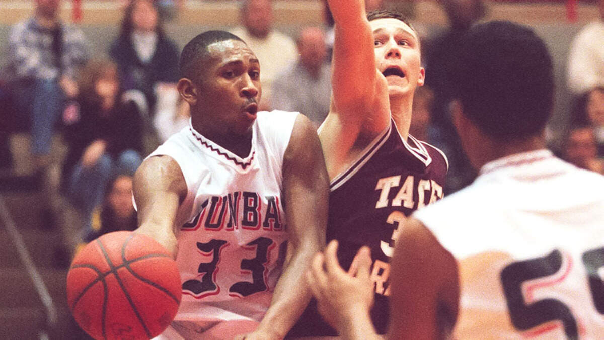 Paul Laurence Dunbar’s George Baker (33) dished around Tates Creek’s John McCord to Alexious Osumenya during a game at Dunbar’s S.T. Roach Sports Center on Jan. 16, 1999. Baker was an all-state player his senior season and his jersey has been retired by Dunbar.