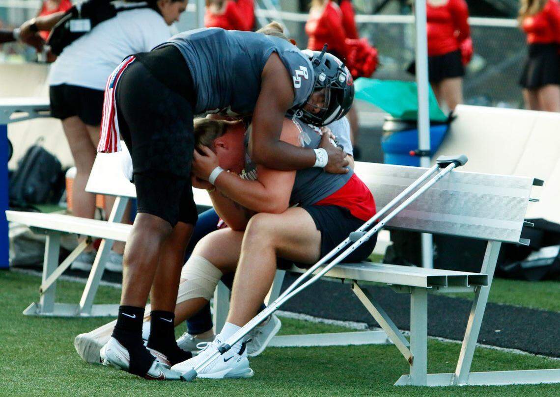 Paul Laurence Dunbar’s Mosses Mafuta, left, hugged teammate Ethan Hampton after the team paid tribute to their injured standout by lining up a man-short on the offensive line in their first game without him in the lineup against Collins on Sept. 1. Hampton said the tributes from the Dunbar community were overwhelming.