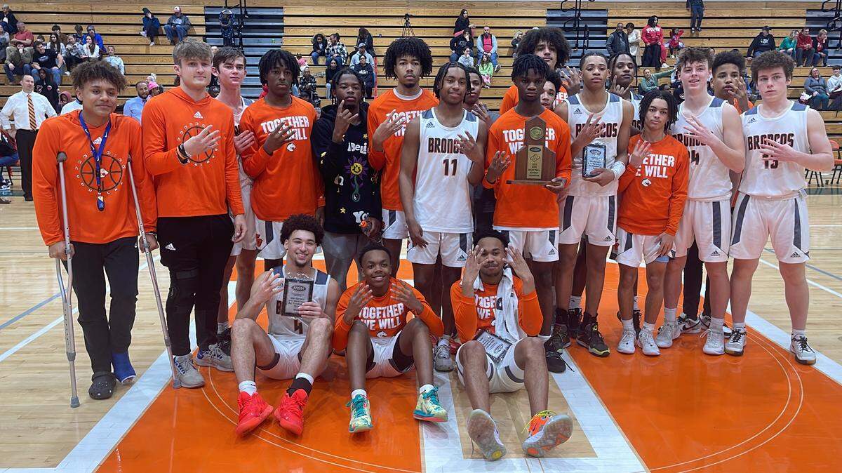 Frederick Douglass players celebrate the program’s fourth consecutive 42nd District Tournament championship by holding up four fingers to signify the feat after beating Scott County 69-39 at Frederick Douglass High School on Friday night.