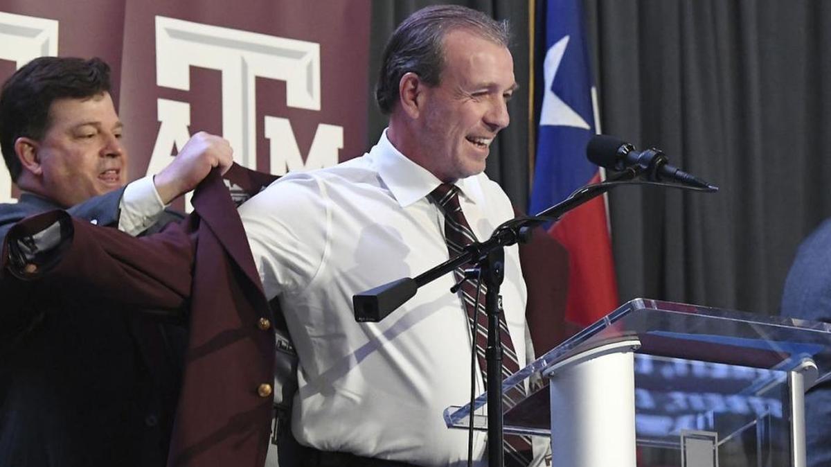 Texas A&M Athletic Director Scott Woodward helps new football coach Jimbo Fisher on with a maroon jacket during Fisher’s introductory press conference in College Station on Monday, Dec. 4, 2017. Fisher left Florida State after eight seasons to become head coach of the Aggies.