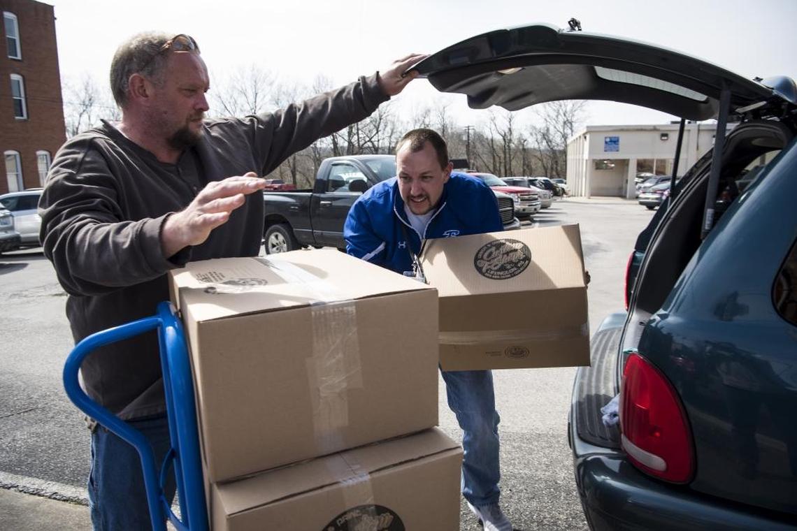 Richard Johnson, left, and Cory Stringfield, right, unload boxes of Estill County 14th Region Basketball Championship T-shirts that were sold at Fan Zone in Irvine last Friday.