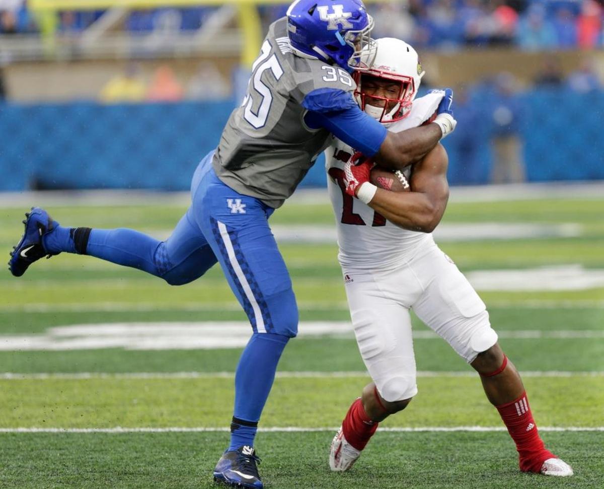 Former Louisville running back L.J. Scott, right, tried to break through the tackle of Kentucky’s Denzil Ware in the 2015 battle for the Governor’s Cup. Now a redshirt junior transfer at Eastern Kentucky, Scott will be part of a deep bevy of EKU running backs.