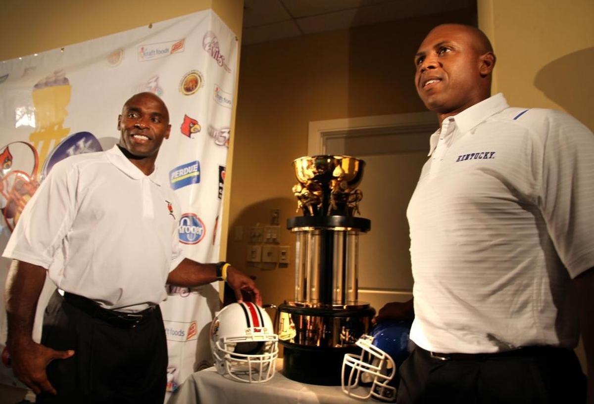 Louisville Coach Charlie Strong, left, and Kentucky head man Joker Phillips posed with the Governor’s Cup trophy at the preseason luncheon before they faced each other for the first time in the UK-U of L rivalry in 2010.