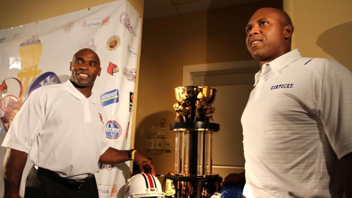 Louisville Coach Charlie Strong, left, and Kentucky head man Joker Phillips posed with the Governor’s Cup trophy at the preseason Governor’s Cup luncheon before they faced each other for the first time in the UK-U of L rivalry in 2010.