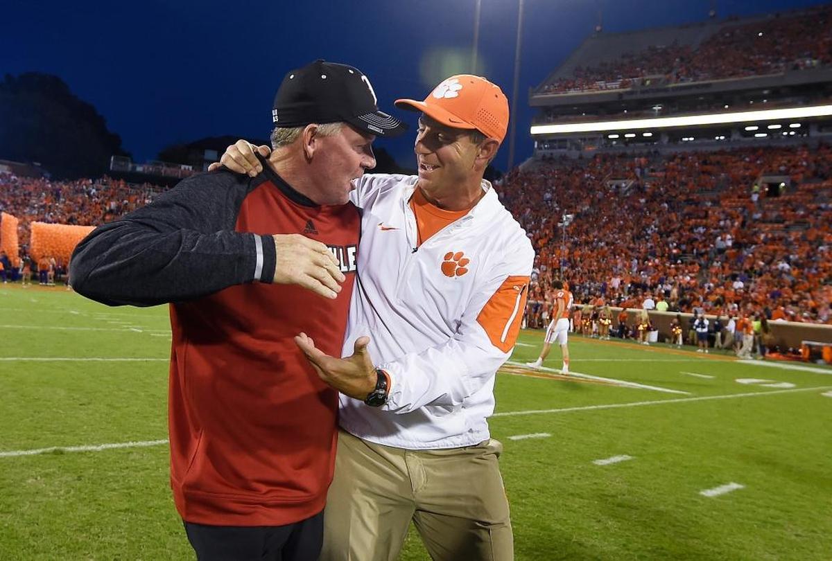 Louisville Coach Bobby Petrino, left, and Clemson head man Dabo Swinney, right, chatted before the Tigers’ 42-36 victory over the Cardinals last year. Since U of L joined the ACC in 2014, the Cards are 0-3 vs. Clemson.