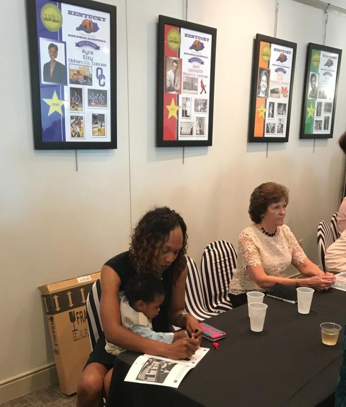 Former Oldham County girls’ basketball star and current University of Kentucky women’s hoops assistant Kyra Elzy held her son, Jackson, while signing autographs at the reception before the 2017 Kentucky High School Basketball Hall of Fame induction.