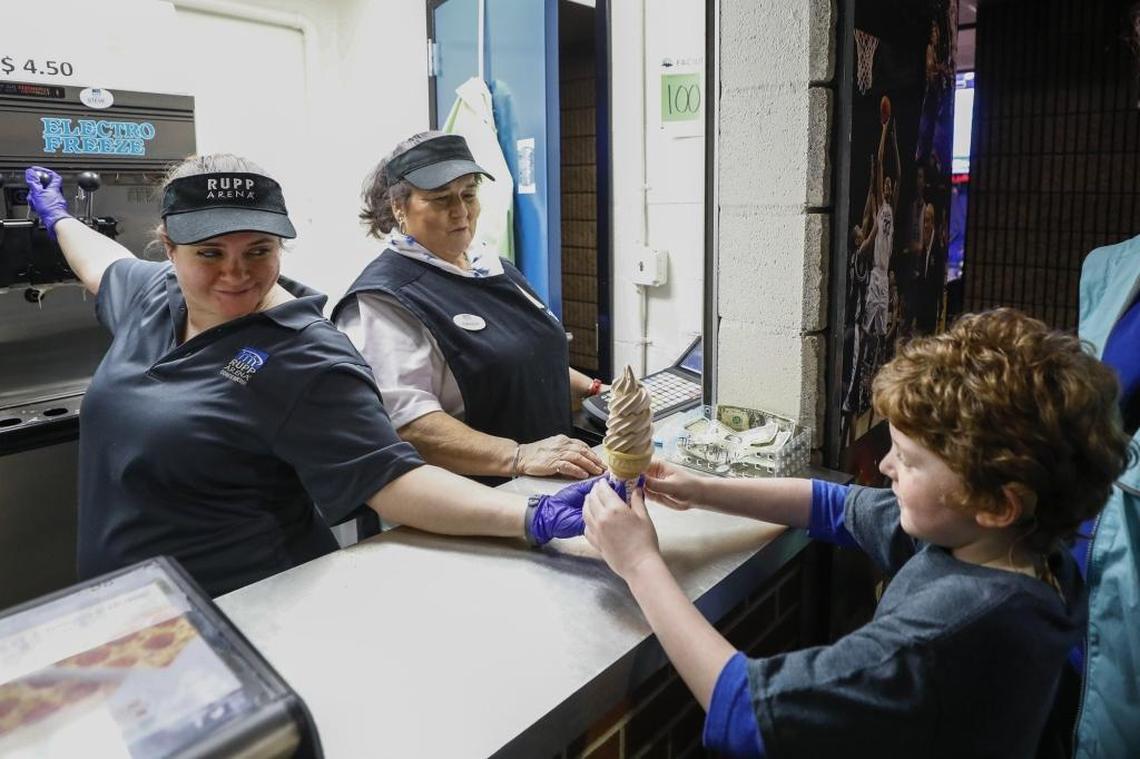 Savannah Hunsucker, of Lexington, left, and Sandy Vanderpool, of Lancaster, delivered a soft-serve ice cream cone to Easton Cahen, 7, of Paducah, before a basketball game between the Kentucky and Missouri in Rupp Arena. The challenge of working in the Rupp ice cream stands is “getting the people out and getting them fed,” Vanderpool says. “They love that ice cream.”