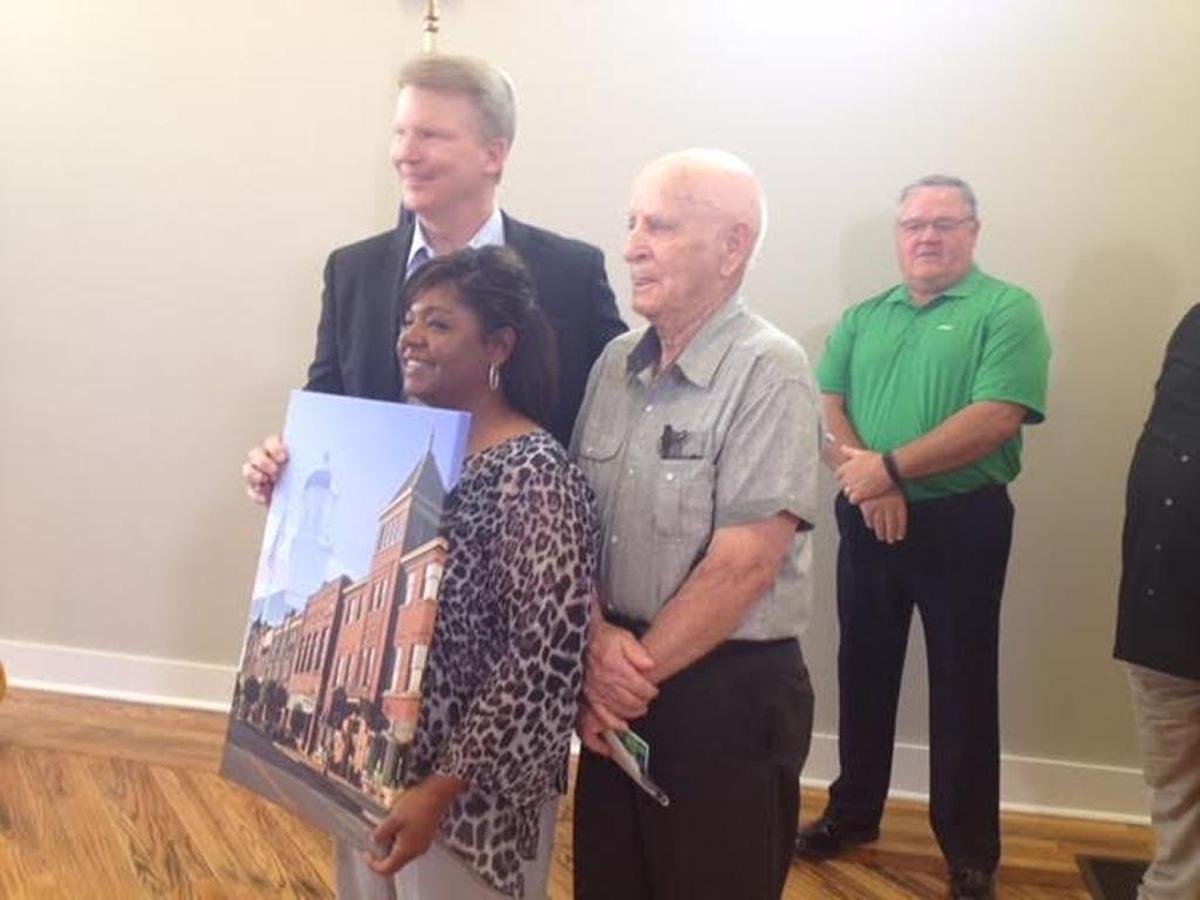 In August, 2015, Springfield Mayor Debbie Wakefiled, front, presented Phil Simms, left, with a streetscape of the town that includes a view of the Springfield Opera House where the Phil Simms Museum is located. Also pictured is Bob Barber, a Springfield Tourism Commission member.